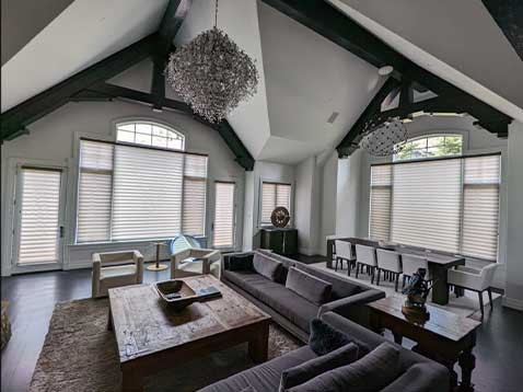 A monochrome, modern living space with large windows covered by shades