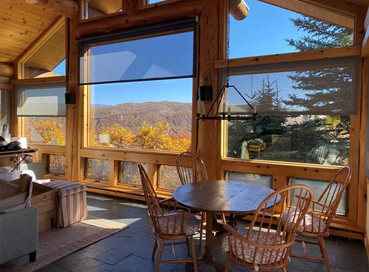A rustic living space showcasing large windows with transparent shades